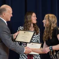 Student shaking hands with Dean Potteiger as they recieve their award, with two other studetns behind them with their awards